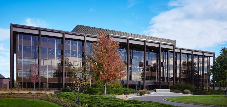 Large building with many windows and pillars against a blue cloudy sky